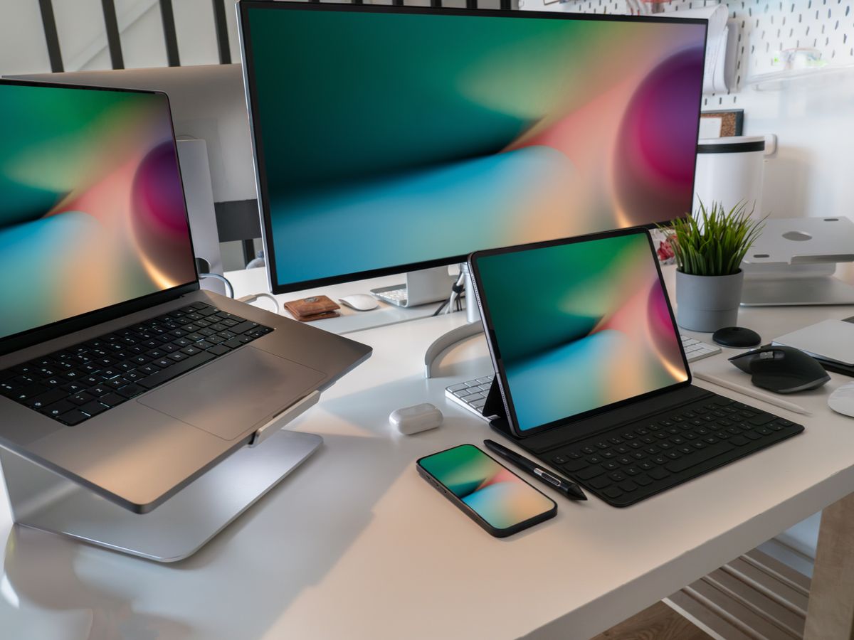 A laptop, tablet and phone on a desk all showing the same wallpaper